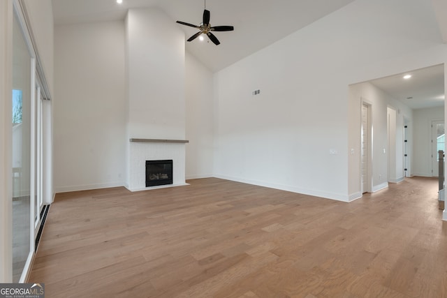 unfurnished living room featuring ceiling fan, a fireplace, high vaulted ceiling, and light hardwood / wood-style floors