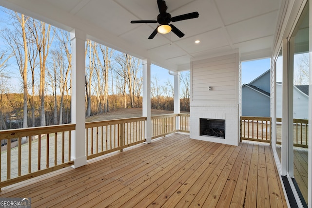 wooden deck featuring an outdoor brick fireplace and ceiling fan