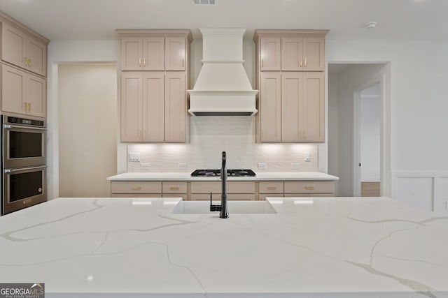 kitchen featuring cream cabinets, custom exhaust hood, and appliances with stainless steel finishes