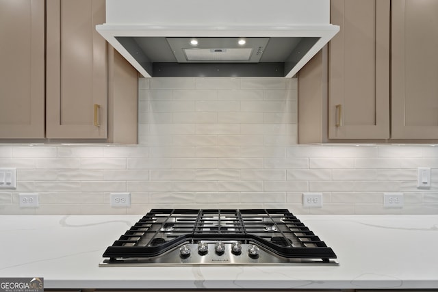 kitchen with tasteful backsplash, extractor fan, stainless steel gas cooktop, and light stone counters