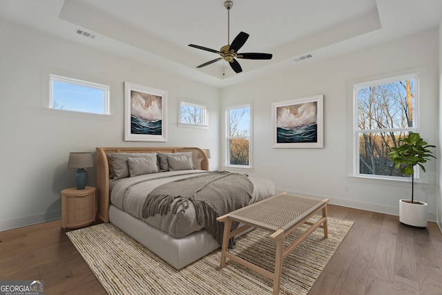 bedroom featuring ceiling fan, a raised ceiling, and hardwood / wood-style floors