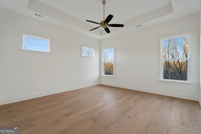 unfurnished room featuring light hardwood / wood-style flooring, a raised ceiling, and ceiling fan