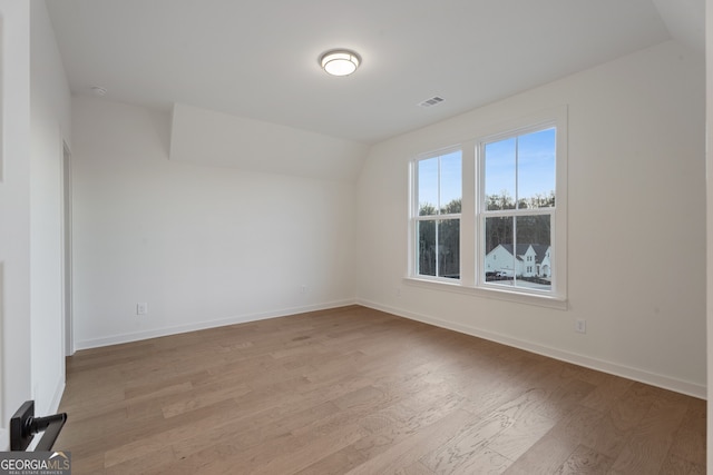 empty room with vaulted ceiling and light hardwood / wood-style floors