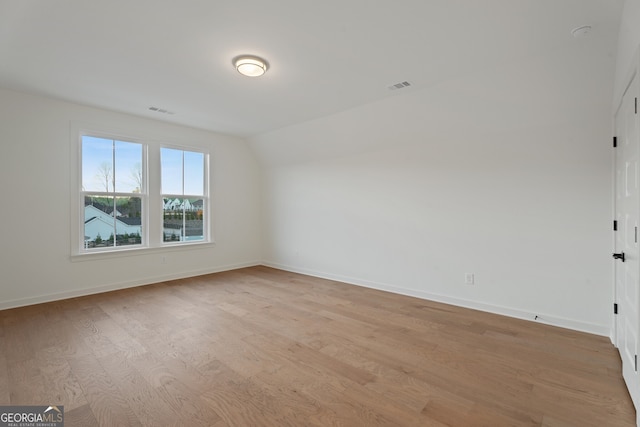 unfurnished room featuring vaulted ceiling and light wood-type flooring