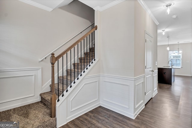 stairway with hardwood / wood-style flooring, an inviting chandelier, ornamental molding, and sink