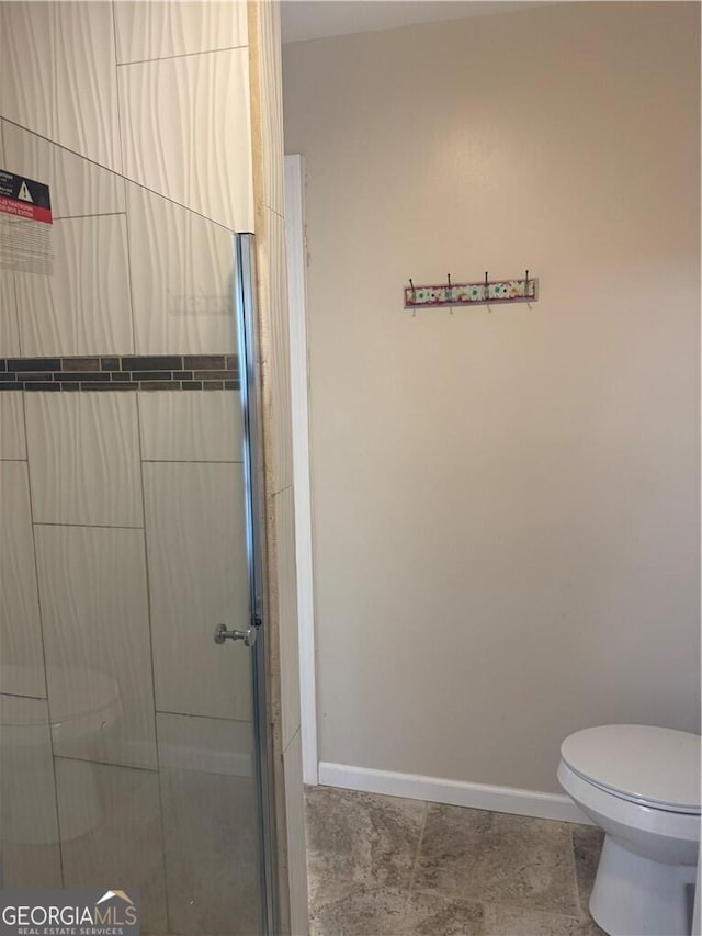 bathroom featuring toilet and a shower with door