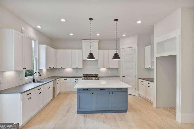 kitchen with pendant lighting, white cabinetry, a kitchen island, and sink