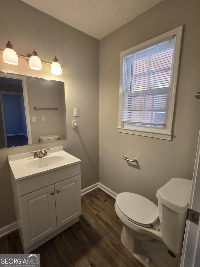 bathroom featuring vanity, a textured ceiling, hardwood / wood-style flooring, and toilet