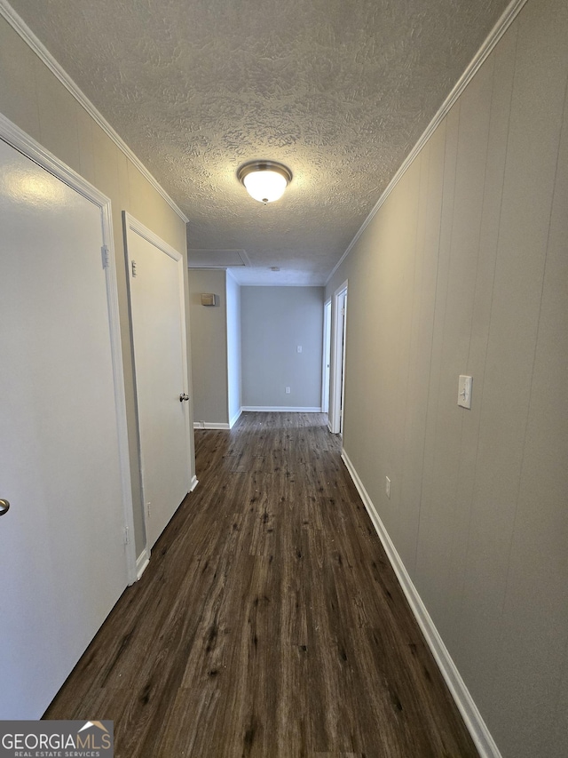 hall with crown molding, wooden walls, dark wood-type flooring, and a textured ceiling