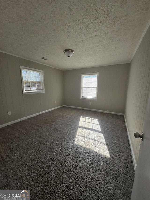 empty room featuring wooden walls and dark carpet