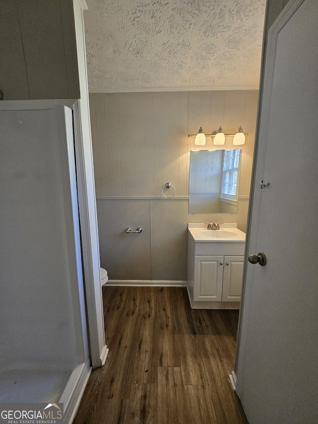 bathroom featuring hardwood / wood-style floors, vanity, toilet, and a textured ceiling