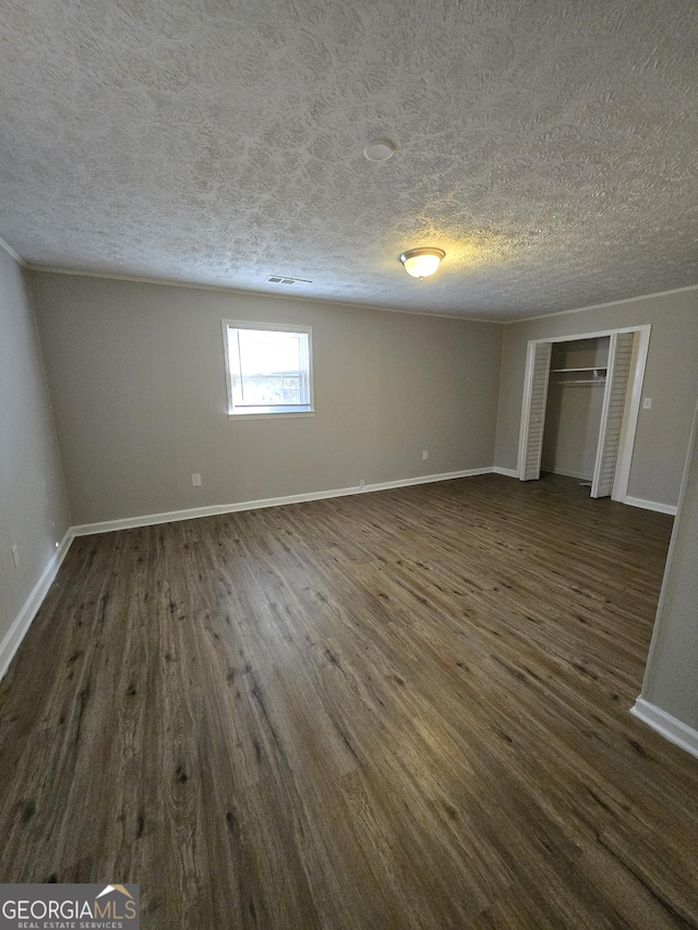 spare room with a textured ceiling and dark hardwood / wood-style floors