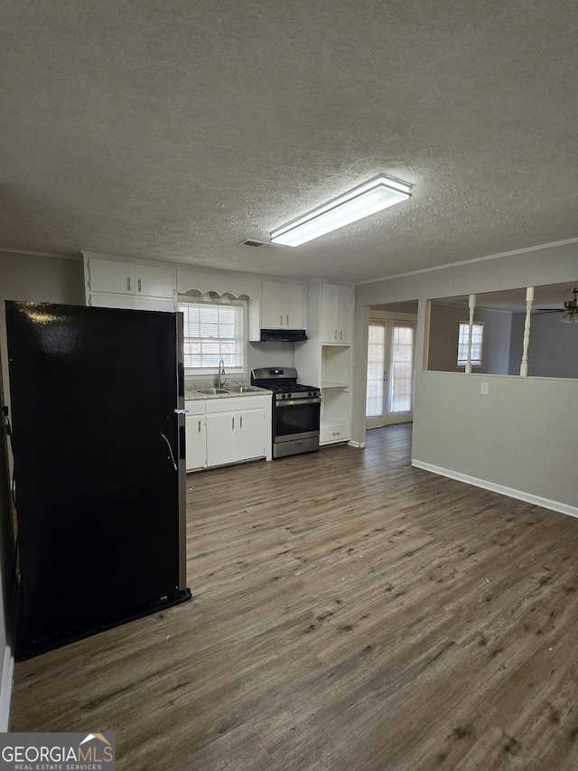 kitchen featuring french doors, black refrigerator, sink, stainless steel gas stove, and white cabinetry