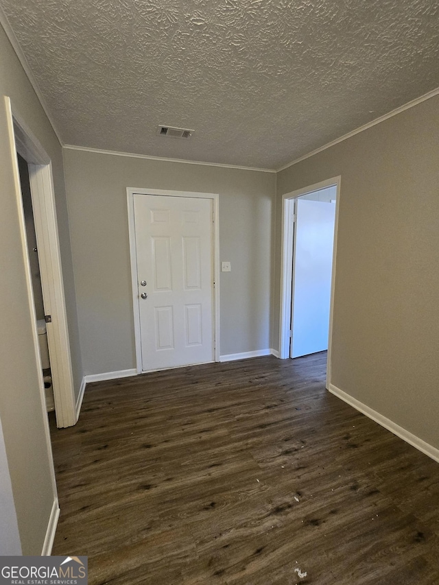 spare room featuring dark hardwood / wood-style flooring, a textured ceiling, and ornamental molding