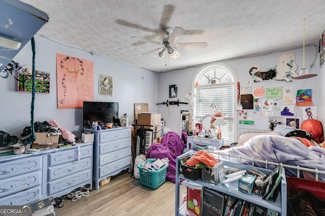 bedroom featuring ceiling fan, light wood-type flooring, and a textured ceiling