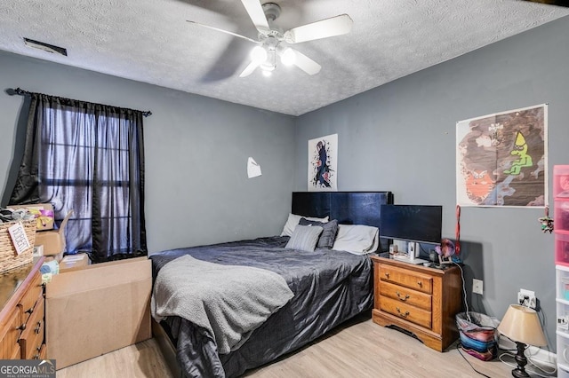 bedroom featuring ceiling fan, light hardwood / wood-style flooring, and a textured ceiling