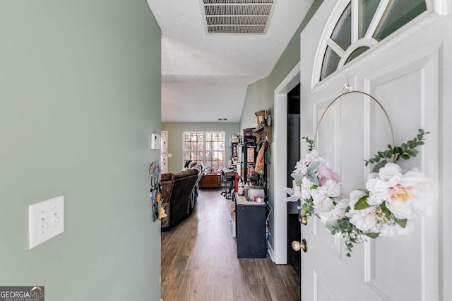 hallway with a textured ceiling, vaulted ceiling, and dark wood-type flooring