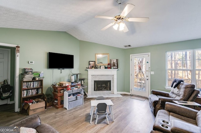 living room featuring ceiling fan, wood-type flooring, a textured ceiling, and vaulted ceiling