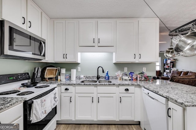 kitchen with kitchen peninsula, a textured ceiling, white appliances, sink, and white cabinets