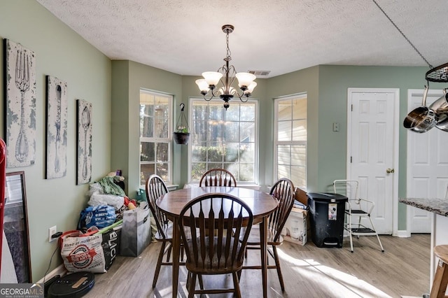 dining space featuring a chandelier, a textured ceiling, and light hardwood / wood-style floors