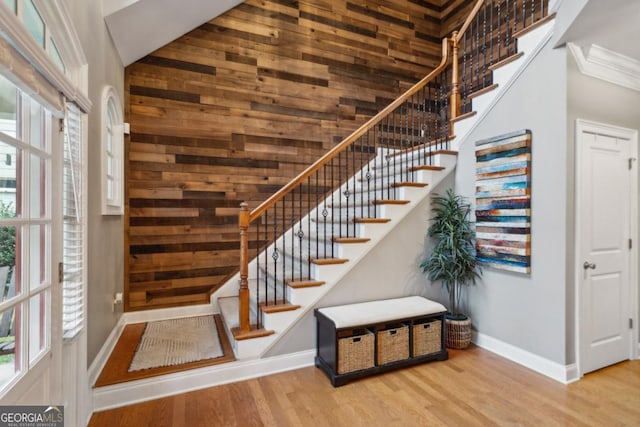 staircase with a towering ceiling, crown molding, wood-type flooring, and plenty of natural light