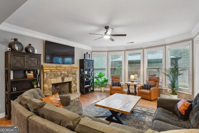 living room featuring a fireplace, light wood-type flooring, ceiling fan, and ornamental molding