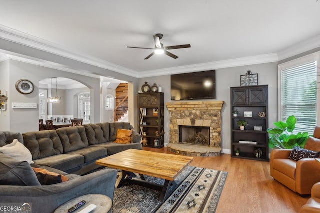 living room with a fireplace, ceiling fan, crown molding, and light hardwood / wood-style flooring