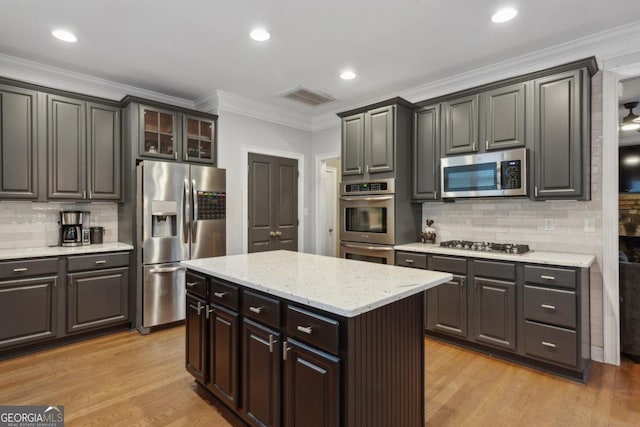 kitchen featuring stainless steel appliances, a kitchen island, ornamental molding, and tasteful backsplash