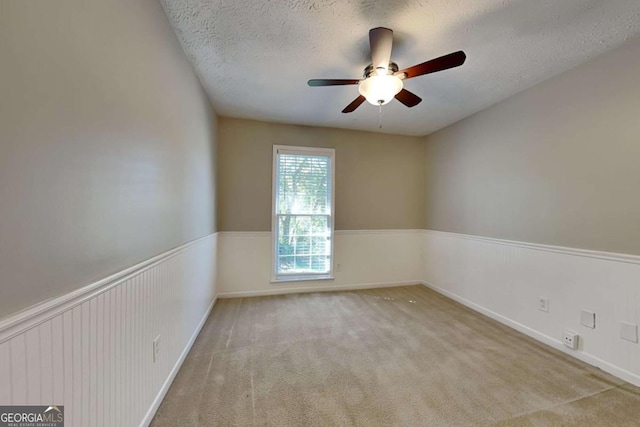 carpeted empty room featuring a textured ceiling and ceiling fan