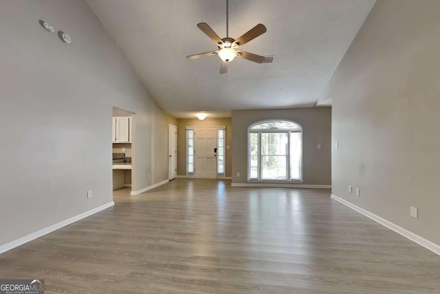 unfurnished living room featuring hardwood / wood-style flooring, ceiling fan, a textured ceiling, and high vaulted ceiling