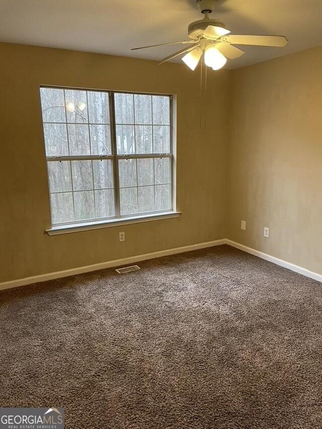 carpeted empty room featuring ceiling fan and plenty of natural light