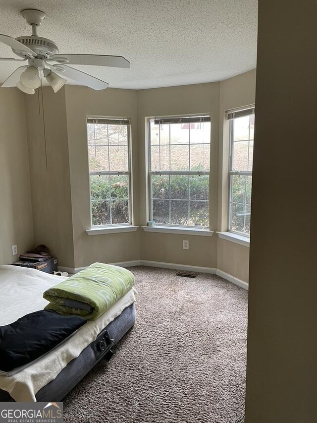 bedroom with ceiling fan, carpet floors, and a textured ceiling