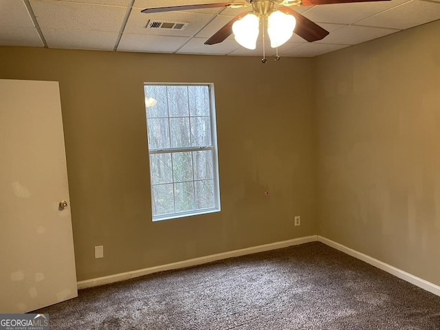 carpeted spare room featuring ceiling fan, a drop ceiling, and a wealth of natural light