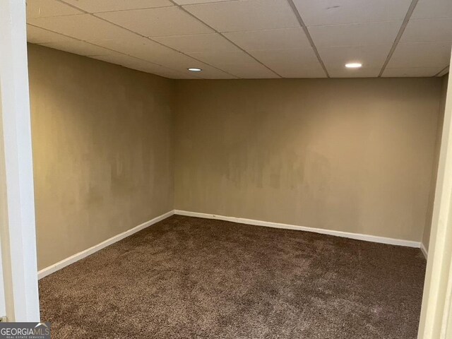 spare room featuring carpet and a drop ceiling