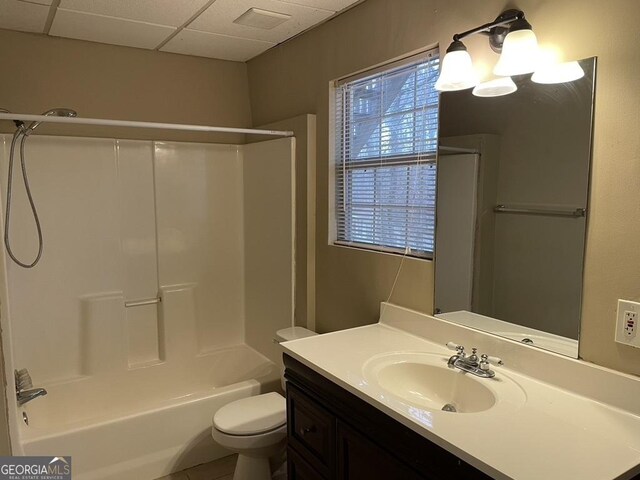 full bathroom featuring a drop ceiling, vanity, bathing tub / shower combination, and toilet