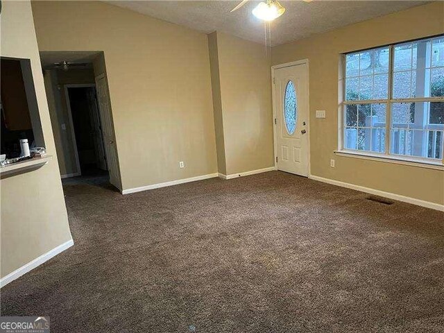 entrance foyer featuring dark colored carpet, vaulted ceiling, and ceiling fan