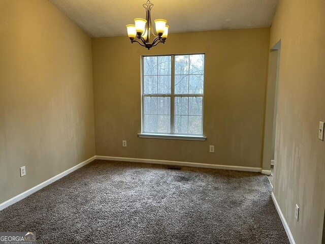 empty room with a chandelier and carpet flooring