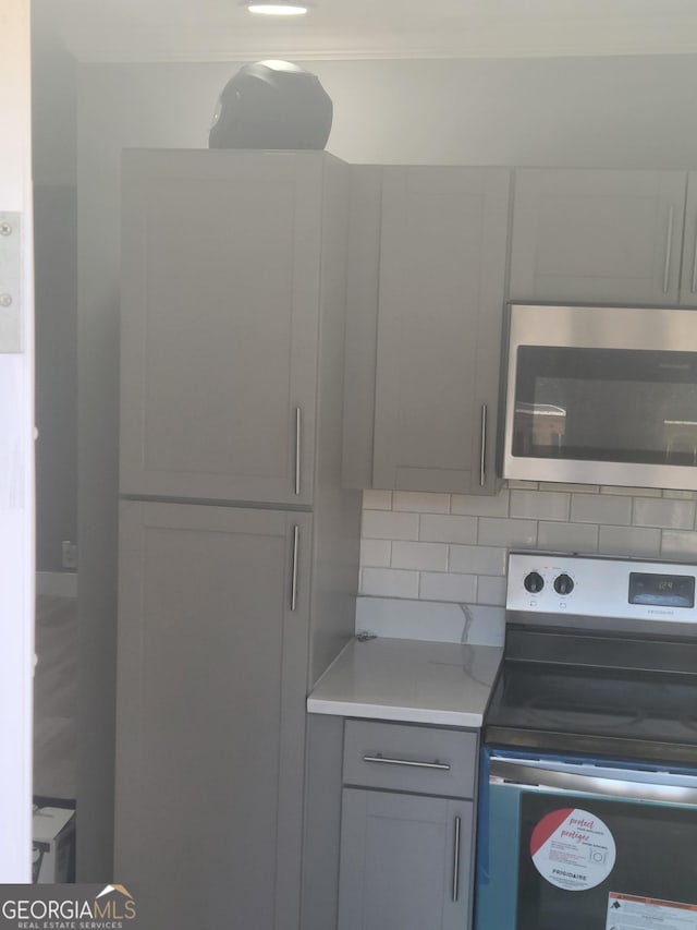 kitchen with stainless steel appliances, decorative backsplash, and gray cabinetry