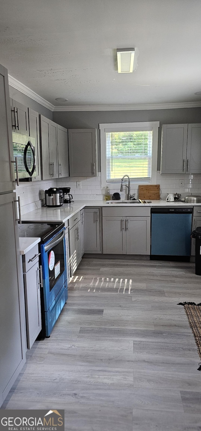 kitchen with gray cabinets, sink, decorative backsplash, stainless steel appliances, and light wood-type flooring