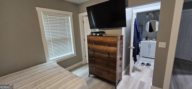 bedroom featuring multiple windows, sink, and light hardwood / wood-style flooring