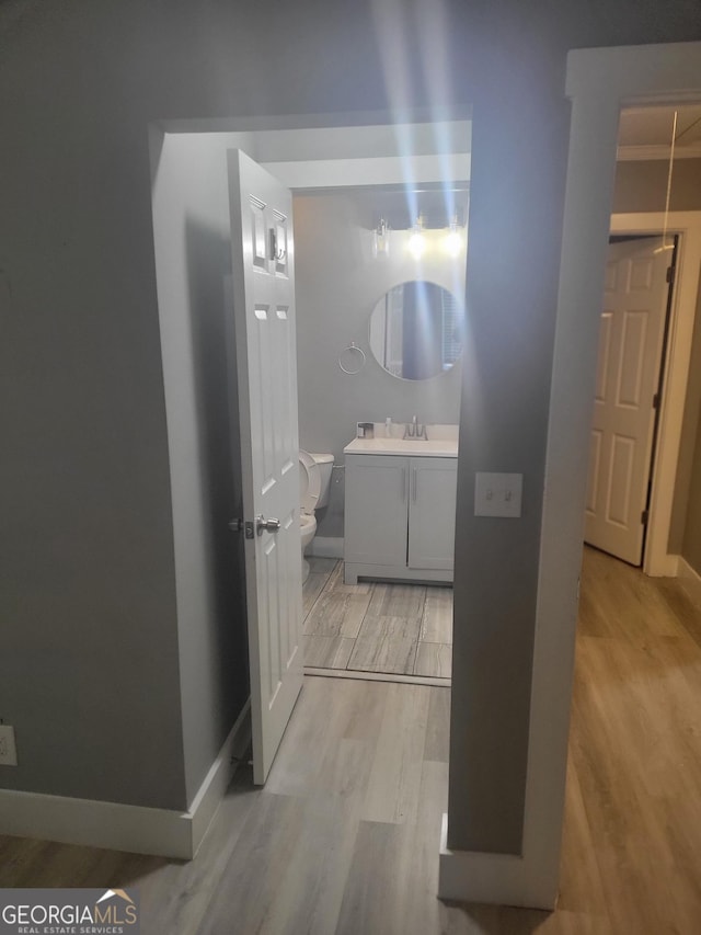 bathroom with wood-type flooring, vanity, crown molding, and toilet