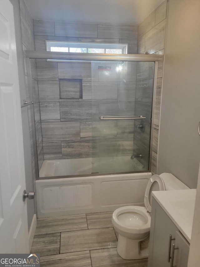 full bathroom with vanity, combined bath / shower with glass door, and toilet