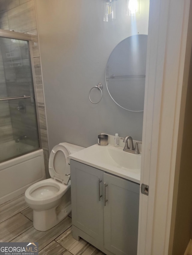 full bathroom featuring vanity, shower / bath combination with glass door, and toilet