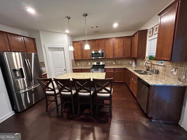 kitchen featuring sink, hanging light fixtures, stainless steel appliances, light stone counters, and dark hardwood / wood-style flooring