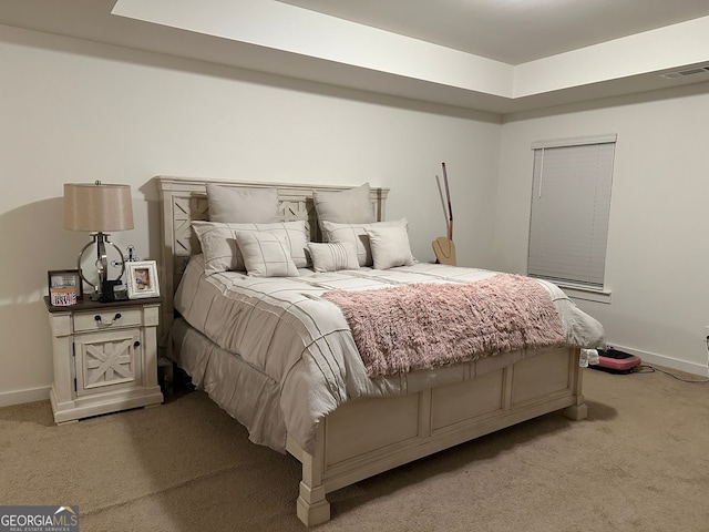 bedroom with light carpet and a raised ceiling