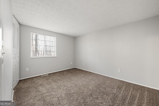 unfurnished room featuring a textured ceiling and carpet