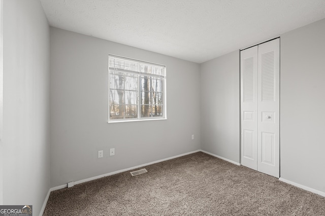 unfurnished bedroom with a textured ceiling, a closet, and carpet flooring