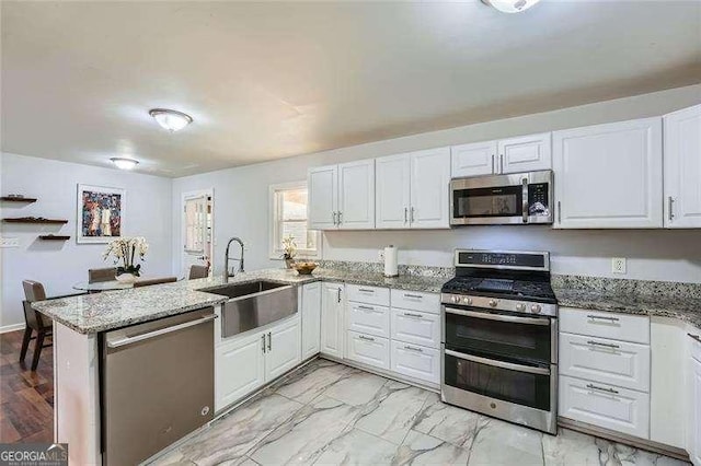 kitchen featuring white cabinets, kitchen peninsula, sink, and appliances with stainless steel finishes