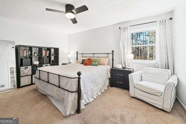 bedroom featuring ceiling fan, light colored carpet, and a textured ceiling