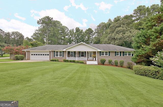 ranch-style home with a porch, a garage, and a front yard